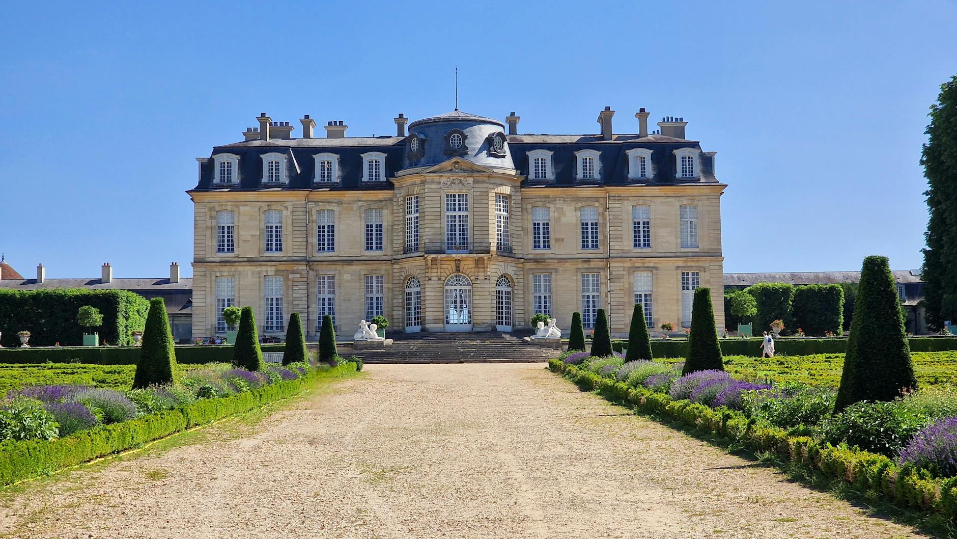 Opulent castle near Paris rivaling Versailles, with grand facade, manicured gardens and fountains