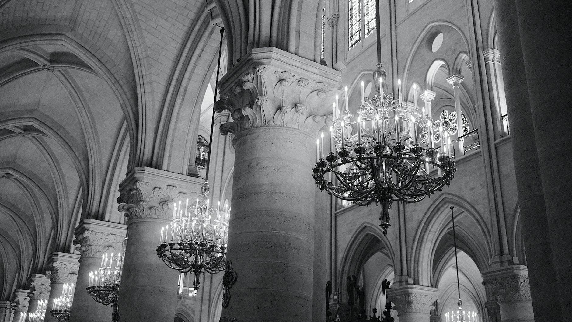 Monochrome interior view of Notre Dame Cathedral with chandeliers and gothic architecture.