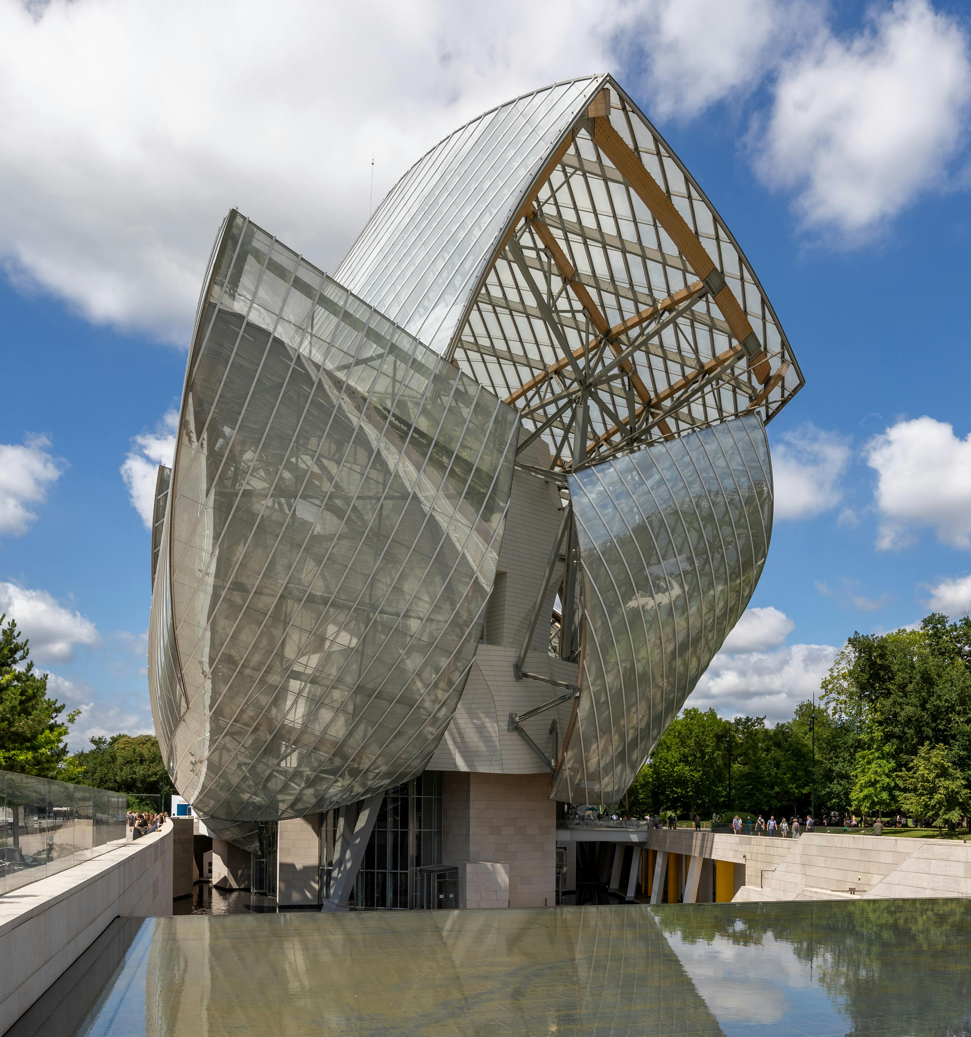 Frank Gehry's Fondation Louis Vuitton glass sails glowing against Bois de Boulogne trees at dusk