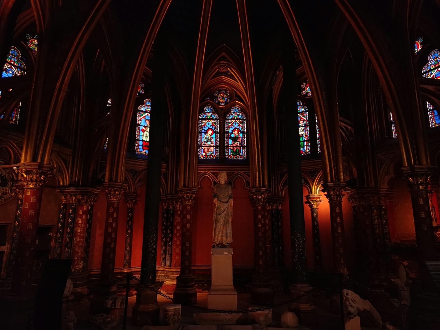 Sainte-Chapelle's stunning stained glass windows illuminated by afternoon light, showcasing intricate biblical scenes in c...