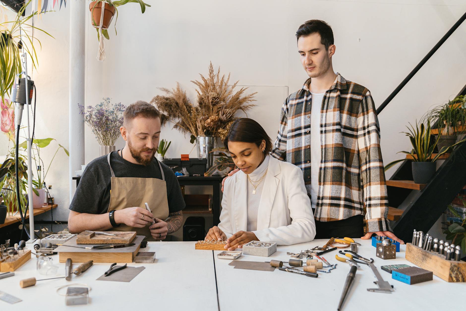 A team of artisans crafting jewelry pieces together in a well-lit studio environment.