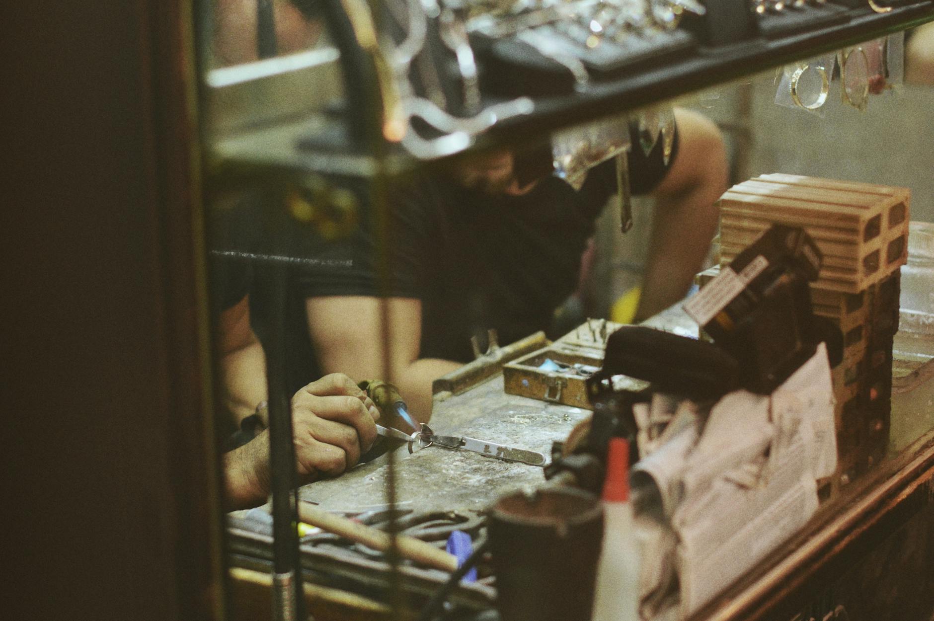Close-up of an artisan at work in a jewelry workshop, focusing on craftsmanship and tools.
