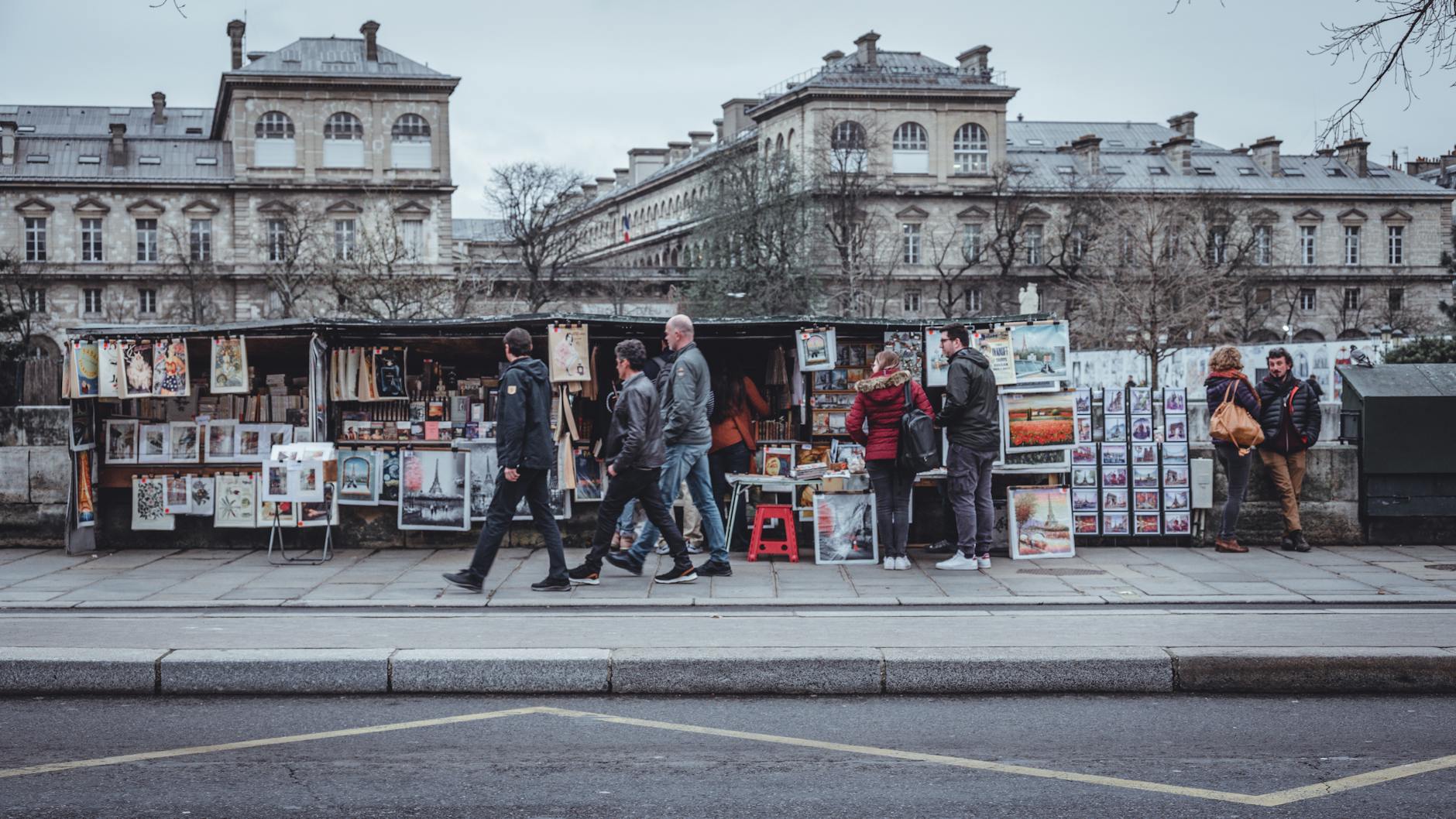 Bustling Paris street with vendors selling art and posters in front of historic buildings.