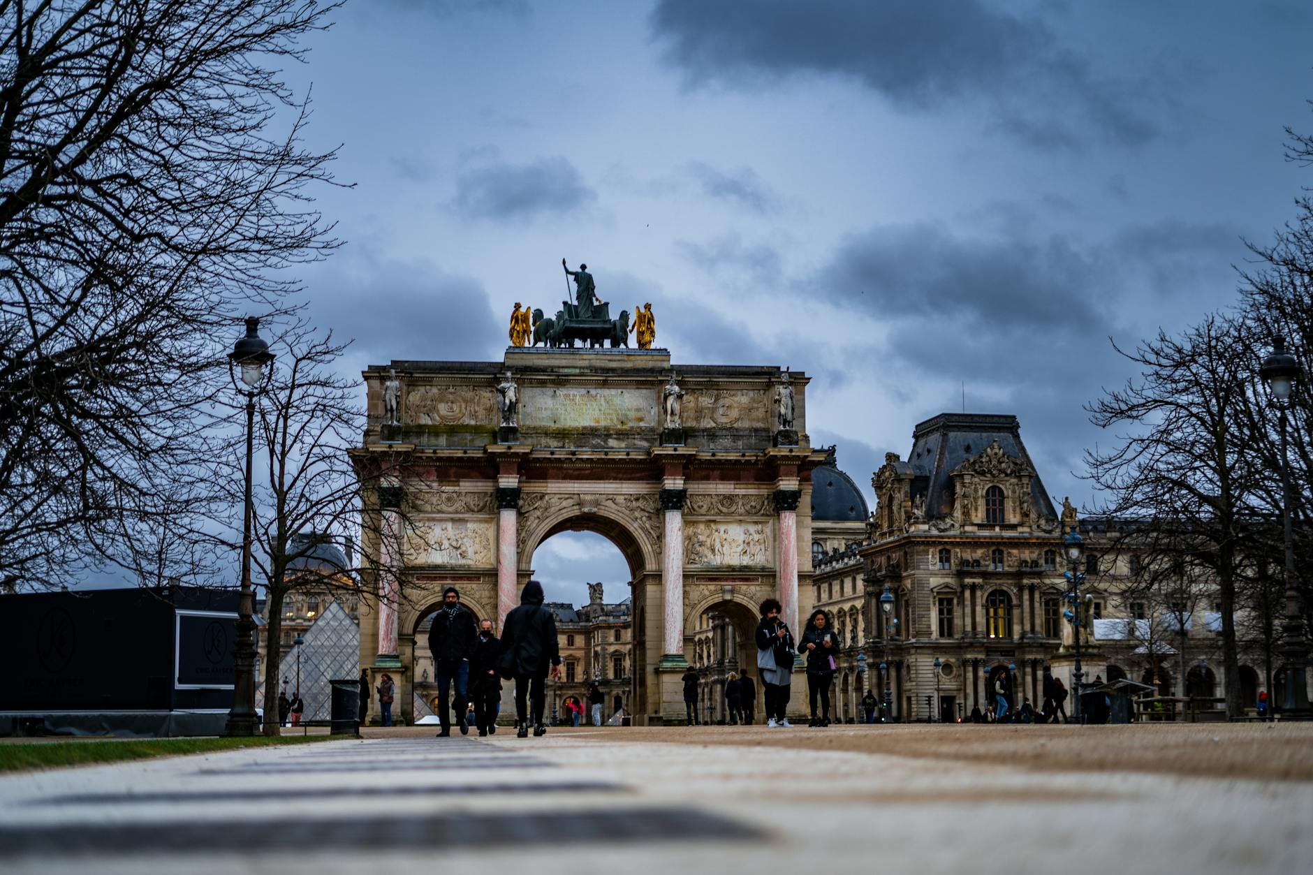 Night view of Arc de Triomphe du Carrousel in Paris with people walking nearby.