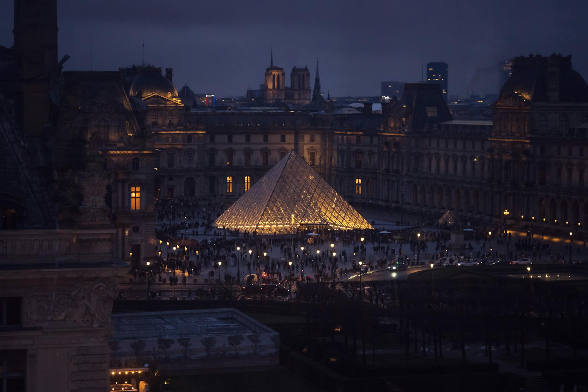 A stunning evening shot of the Louvre Pyramid in Paris, illuminated against the night.