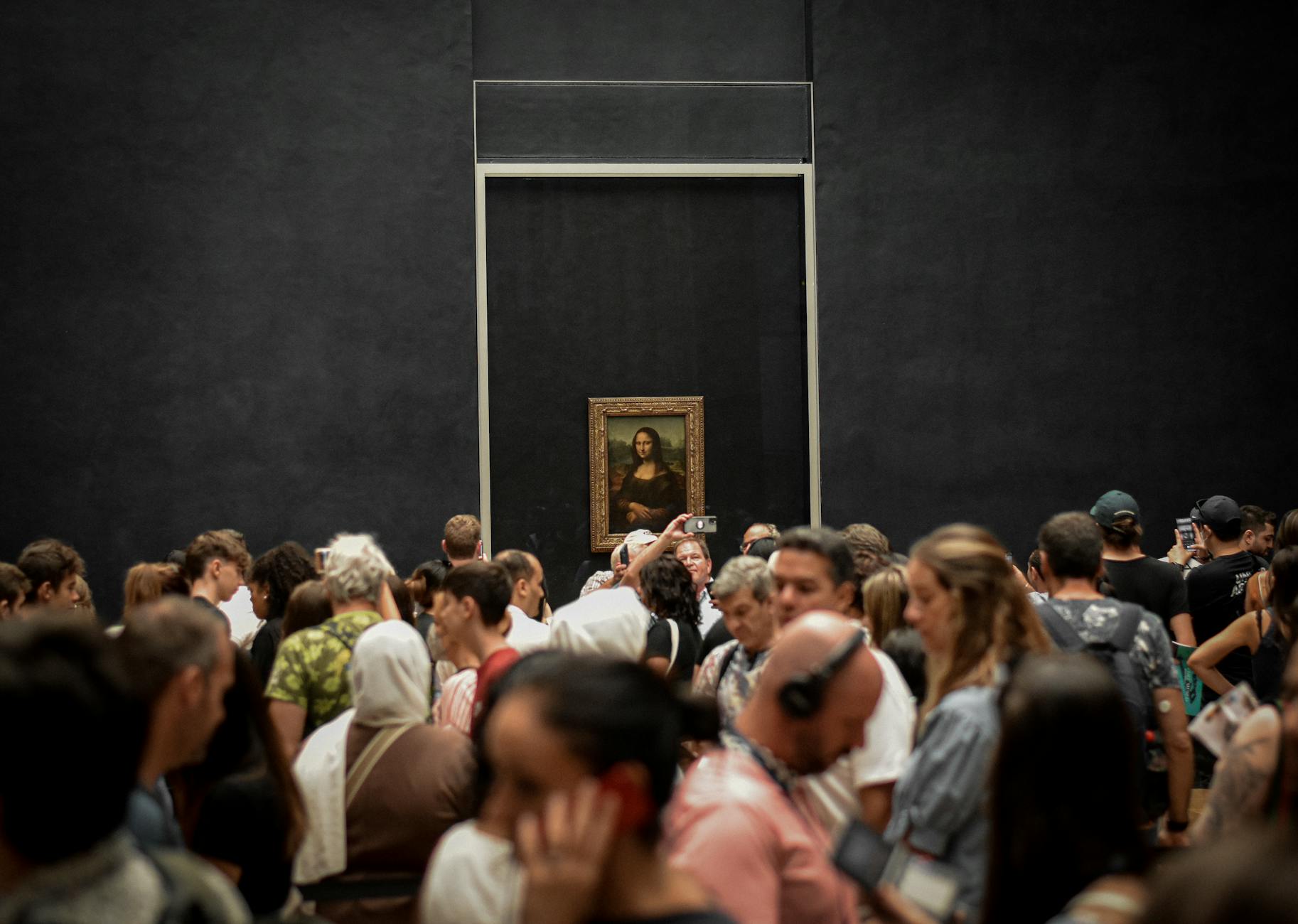 Crowd of tourists taking photos of Mona Lisa painting at the Louvre Museum, Paris.