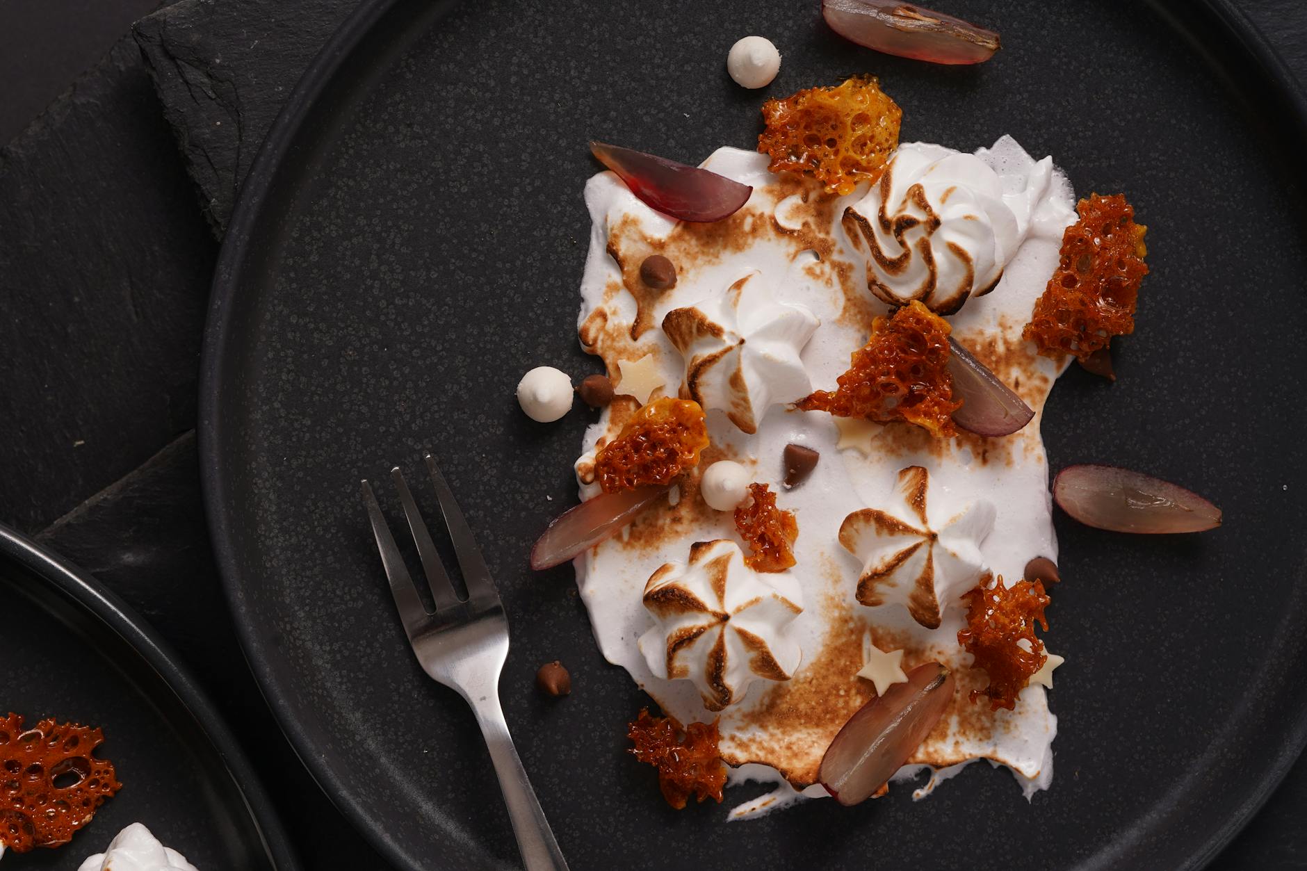 Artistic dessert featuring honeycomb and cream on a dark plate.