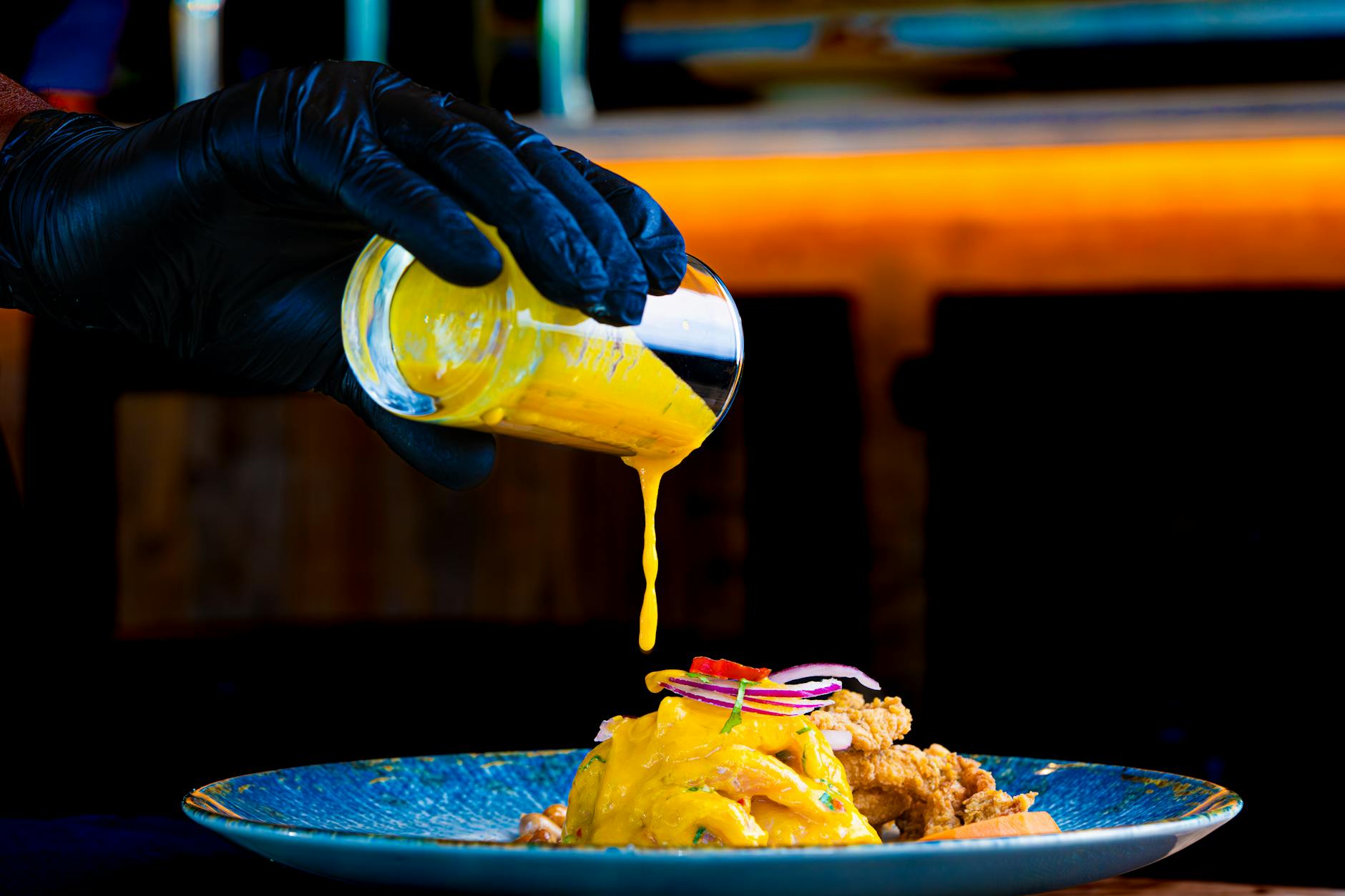 Chef pouring vibrant yellow sauce on gourmet dish. Perfect for culinary and food photography.