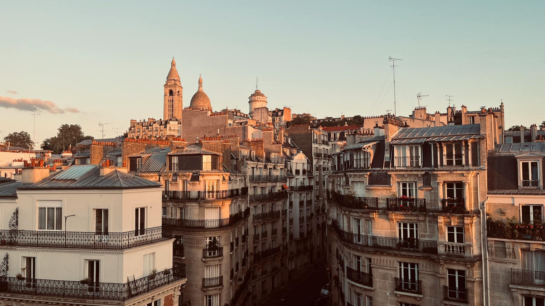 Aerial view of Parisian architecture and the Sacré-Cœur Basilica at sunset, showcasing classic urban beauty.