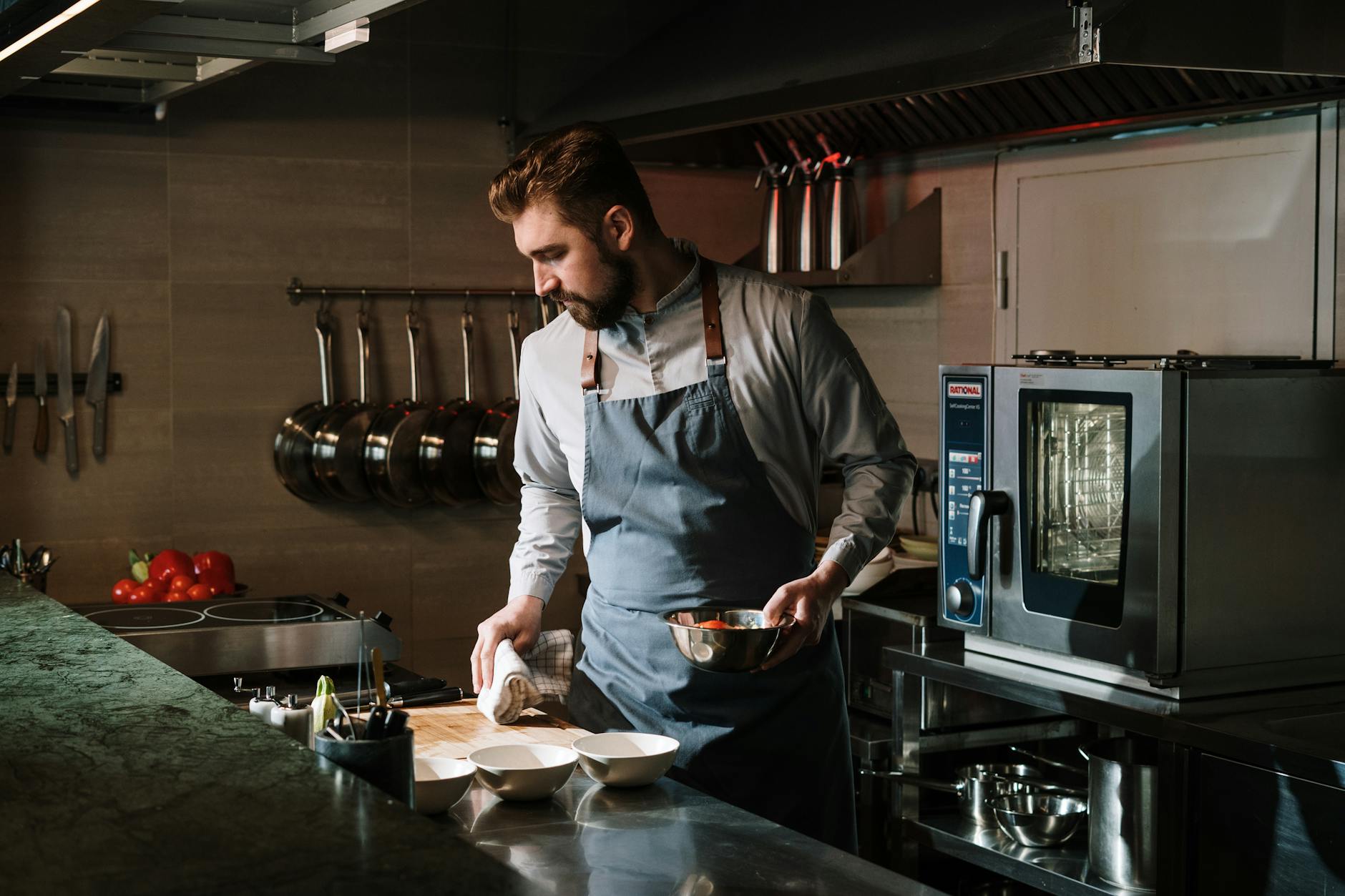 Male chef in a restaurant kitchen preparing a dish, showcasing culinary skills and expertise.