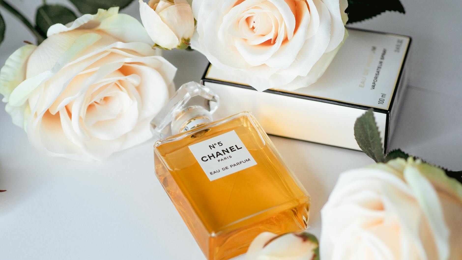 Chanel No. 5 perfume bottle surrounded by elegant white roses showcasing luxury and sophistication.