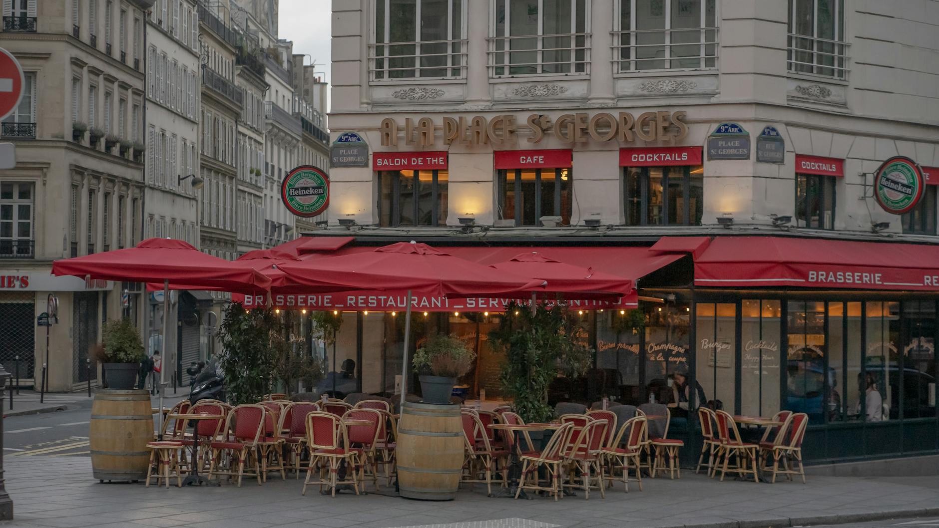 Cozy outdoor seating at a Parisian cafe with red awnings and classic architecture.