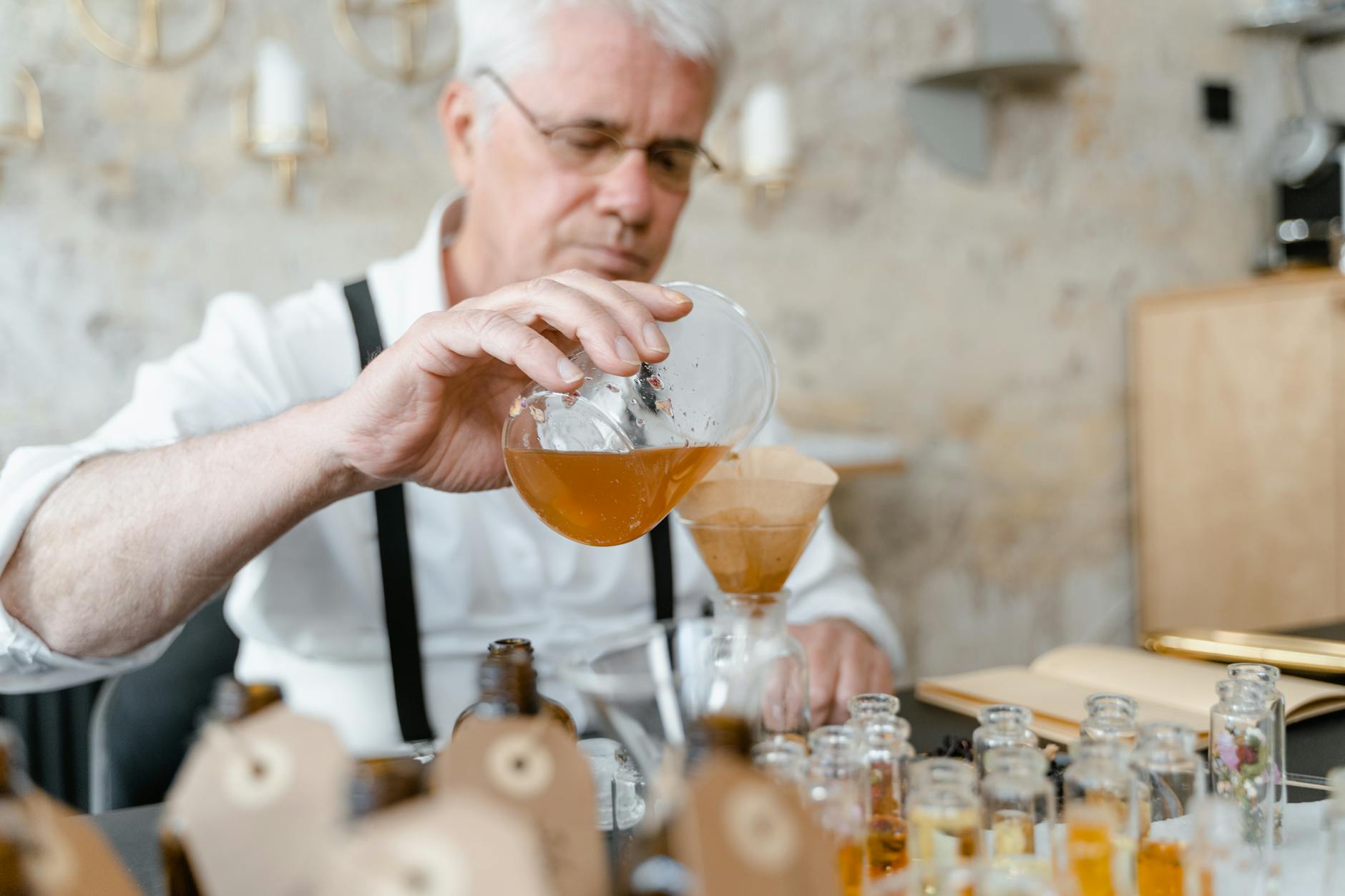 Senior man carefully blends ingredients to create perfume in a cozy workshop.