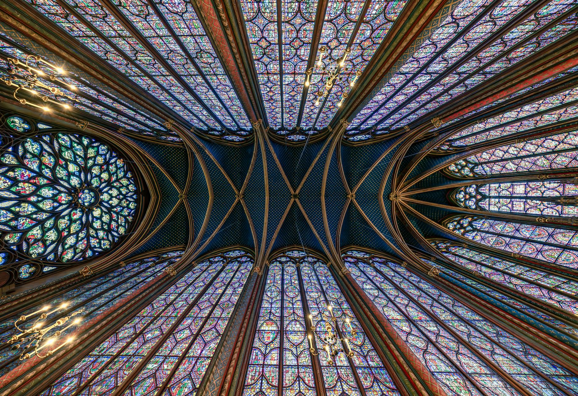 Intricate stained glass ceiling of Sainte Chapelle in Paris displaying Gothic architecture.