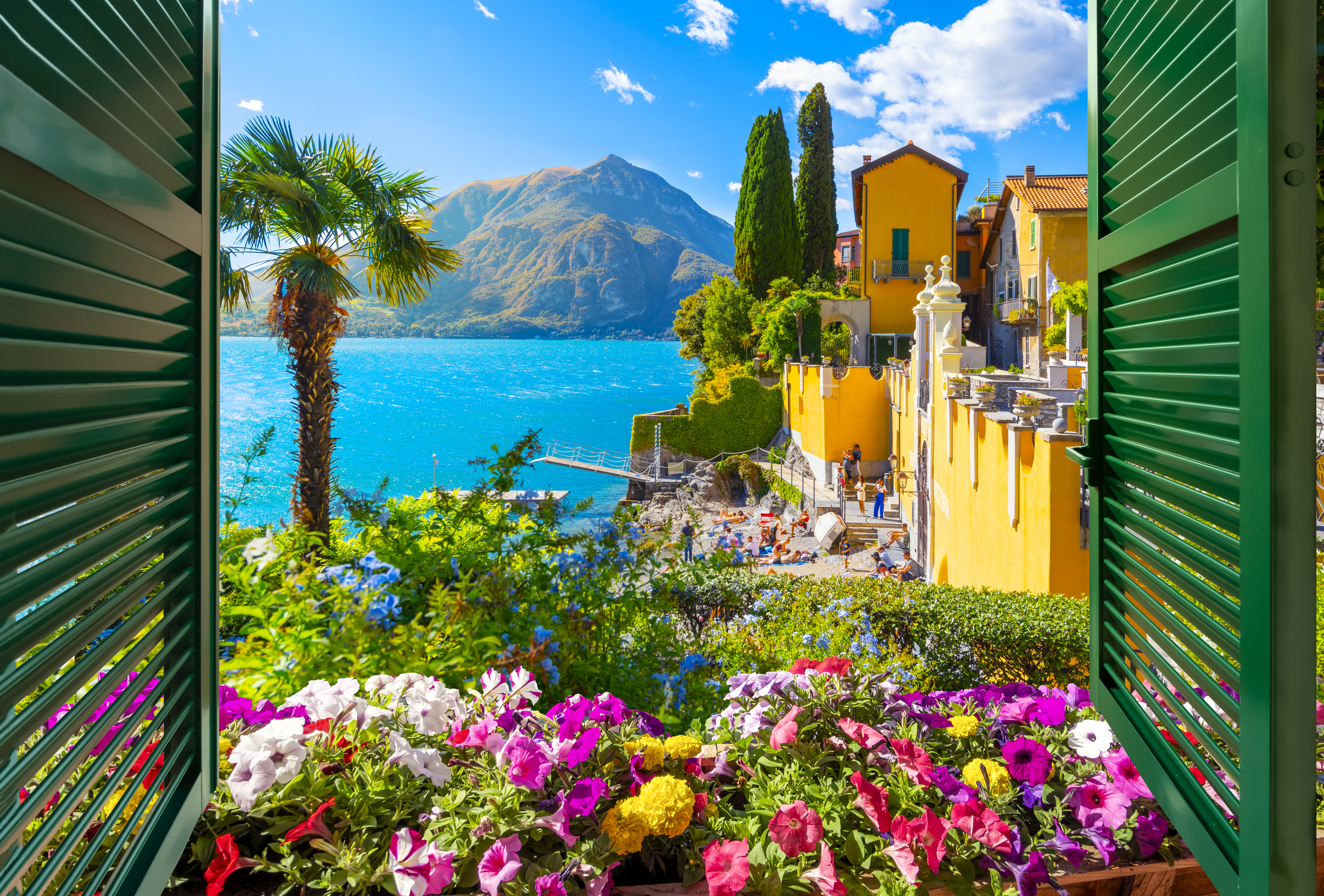 Sunny view of Lake Como from a window with beautiful yellow house and flowers, Italian Lakes, Italy