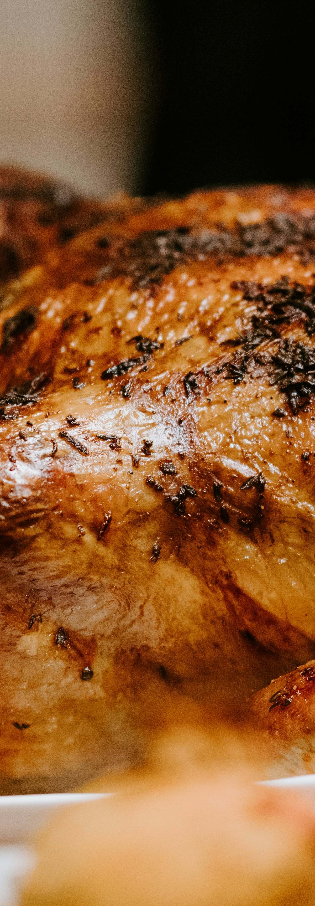 Golden roast chicken on rotisserie spit with herb glaze and potatoes, evoking Parisian rôtisserie charm