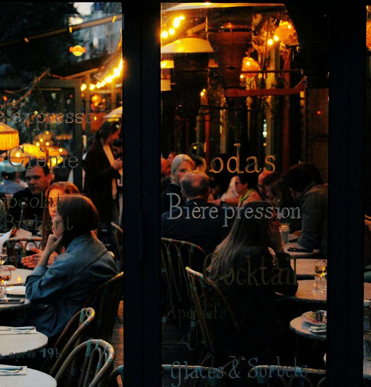 A vibrant café scene in Paris with people enjoying an evening at candlelit tables.