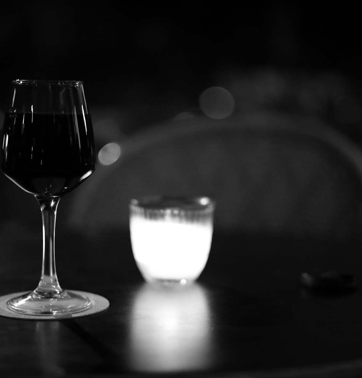 A glass of wine and a candle on a table in a Paris café setting at night.