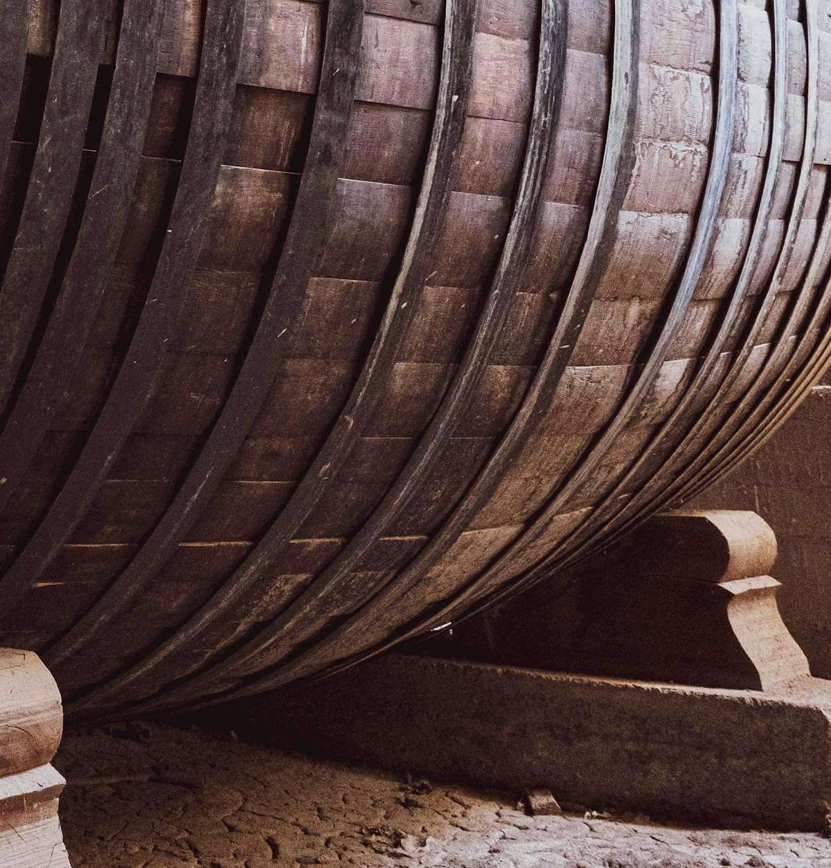 Close-up of a large wooden wine barrel in an ancient wine cellar, highlighting the historic architecture.