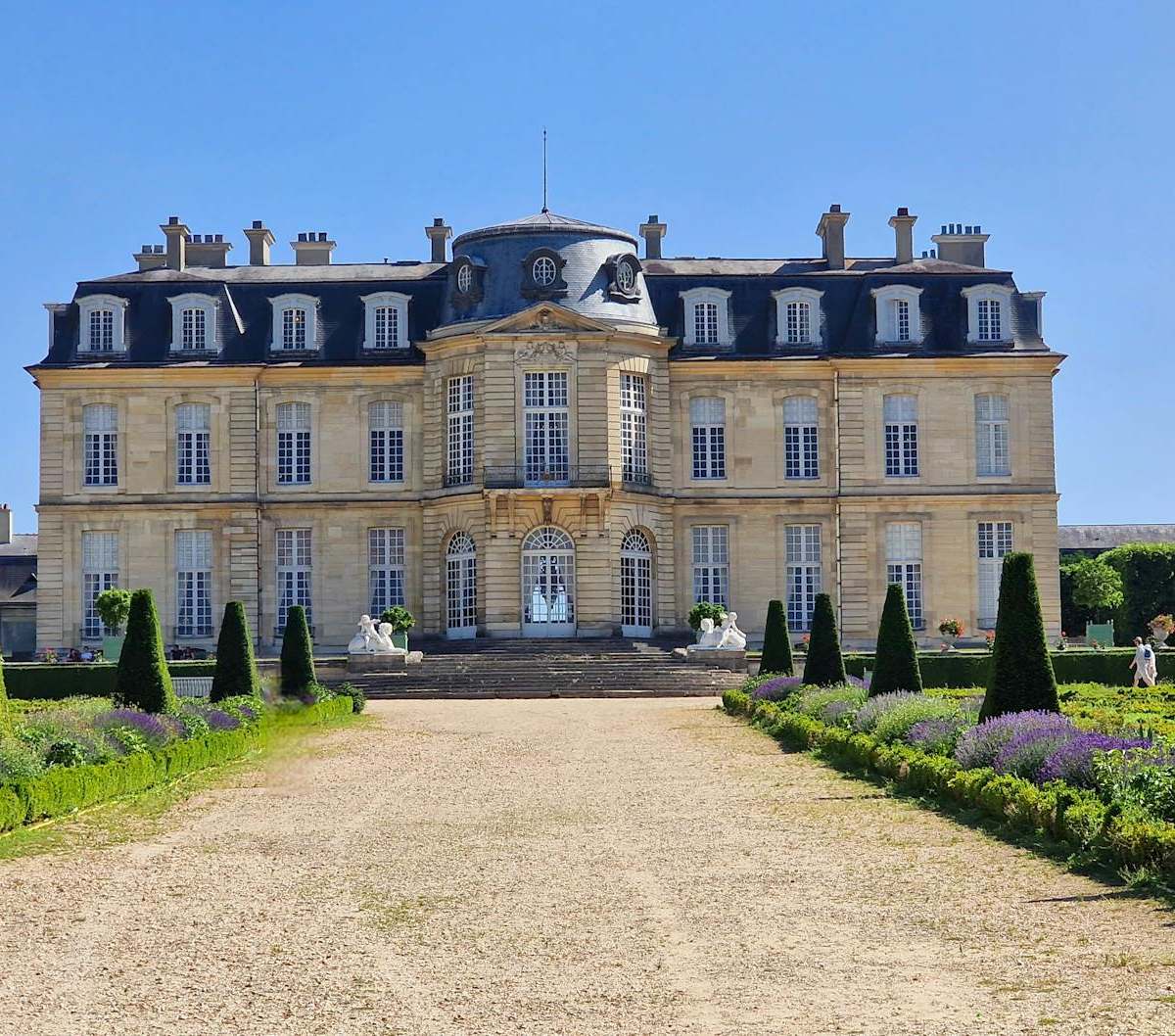 Opulent castle near Paris rivaling Versailles, with grand facade, manicured gardens and fountains