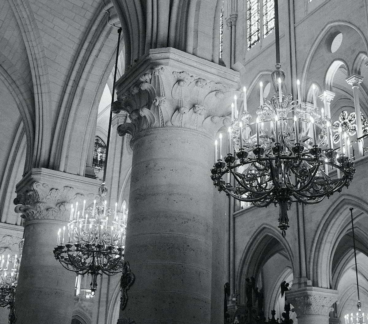 Monochrome interior view of Notre Dame Cathedral with chandeliers and gothic architecture.