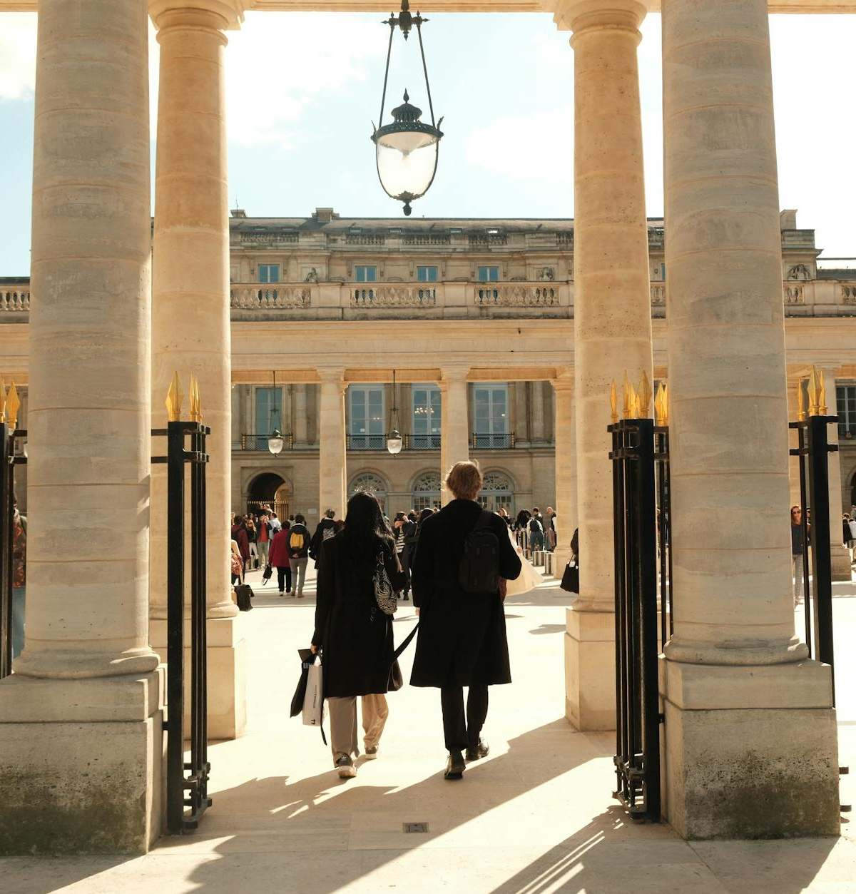 A bustling courtyard in Paris, featuring architectural columns and people enjoying the day.