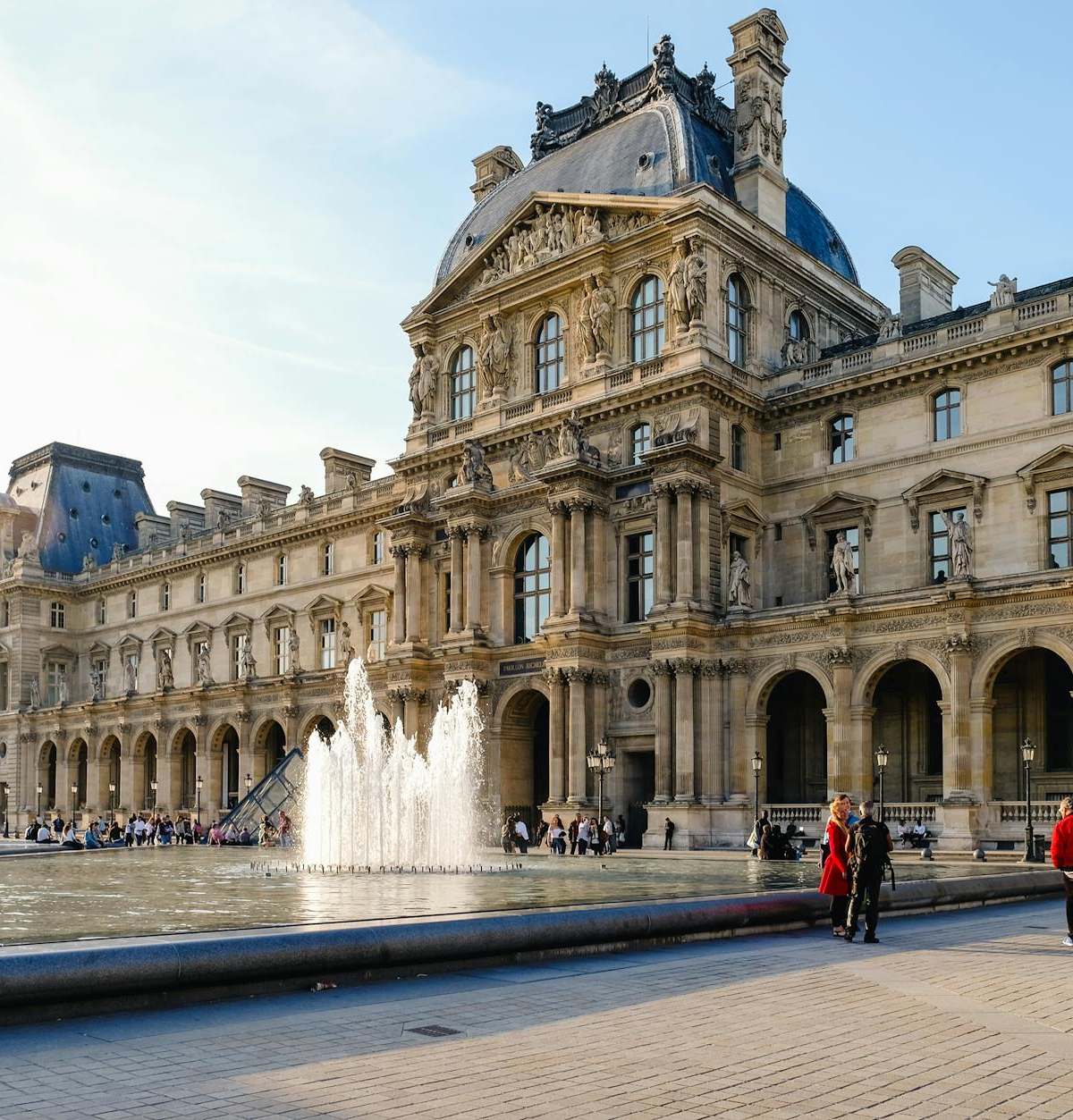 View of the Louvre Museum with a fountain in the courtyard, a popular tourist spot in Paris.