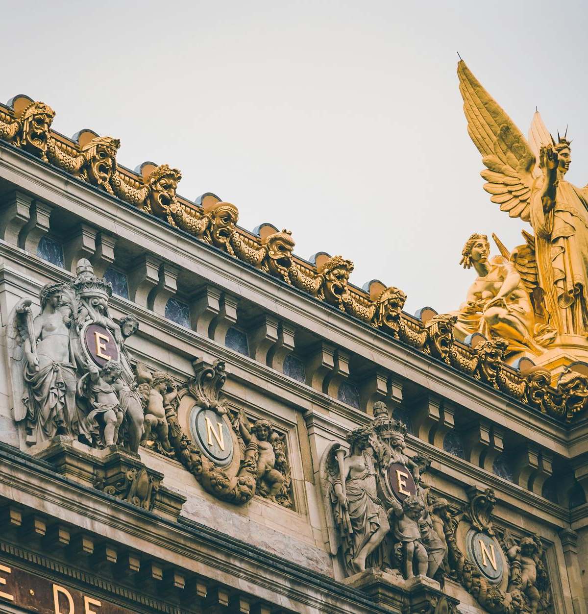 Low angle view of ornate sculptures and golden statues at Palais Garnier, Paris.