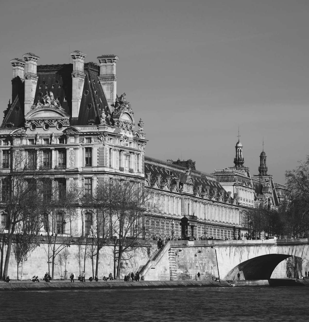 Elegant architecture of Paris captured beside the Seine River in a classic black and white tone.