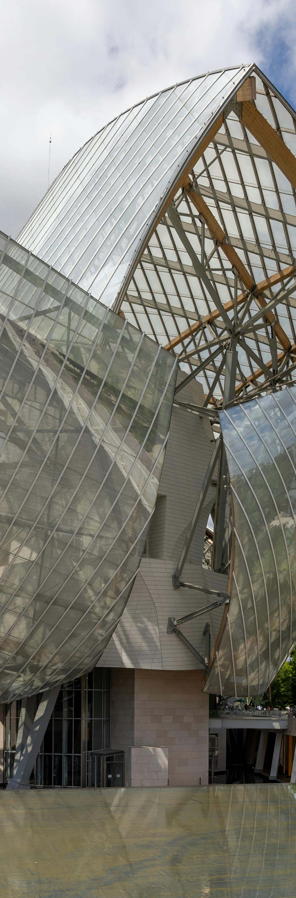 Frank Gehry's Fondation Louis Vuitton glass sails glowing against Bois de Boulogne trees at dusk