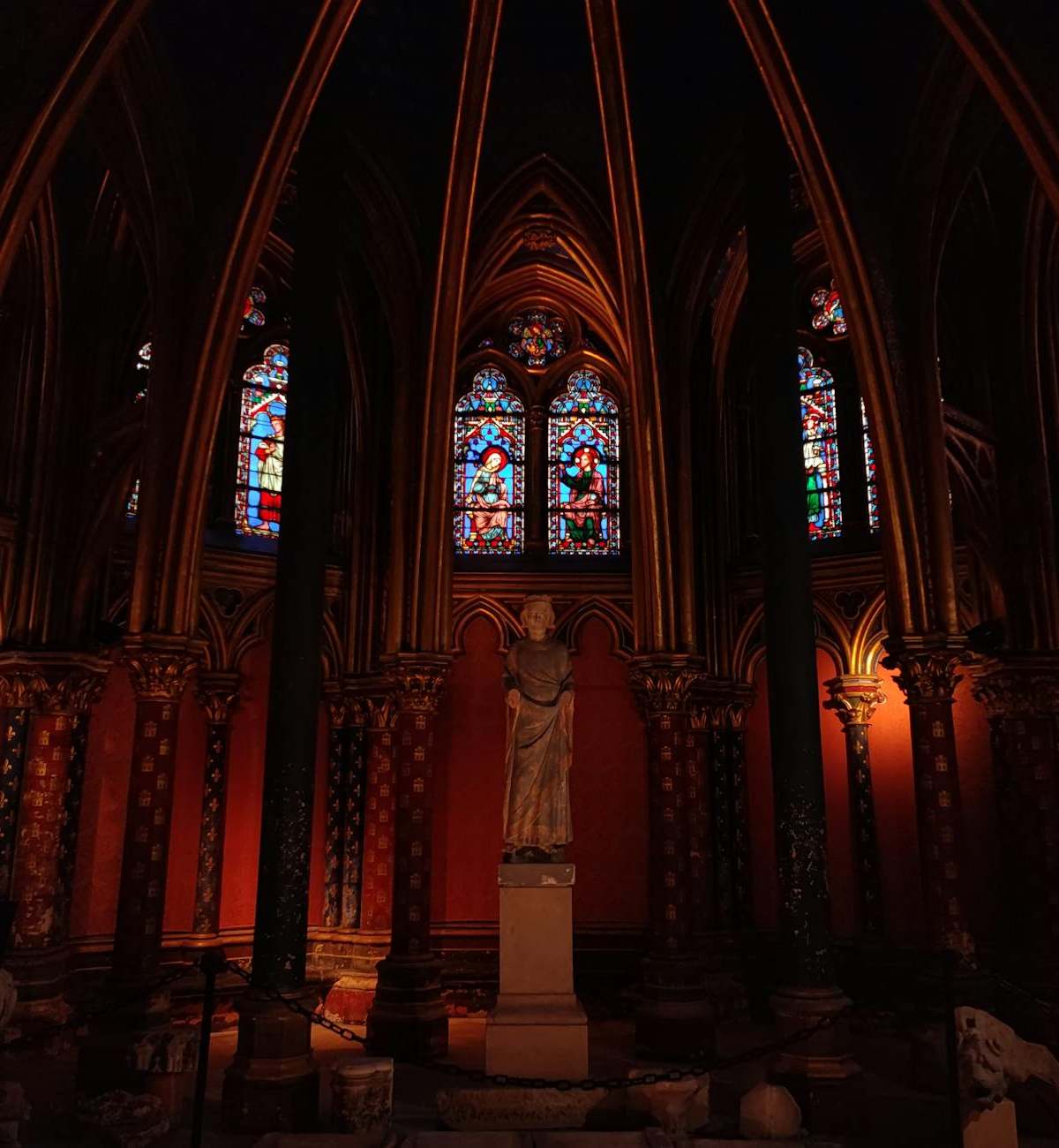 Sainte-Chapelle's stunning stained glass windows illuminated by afternoon light, showcasing intricate biblical scenes in c...
