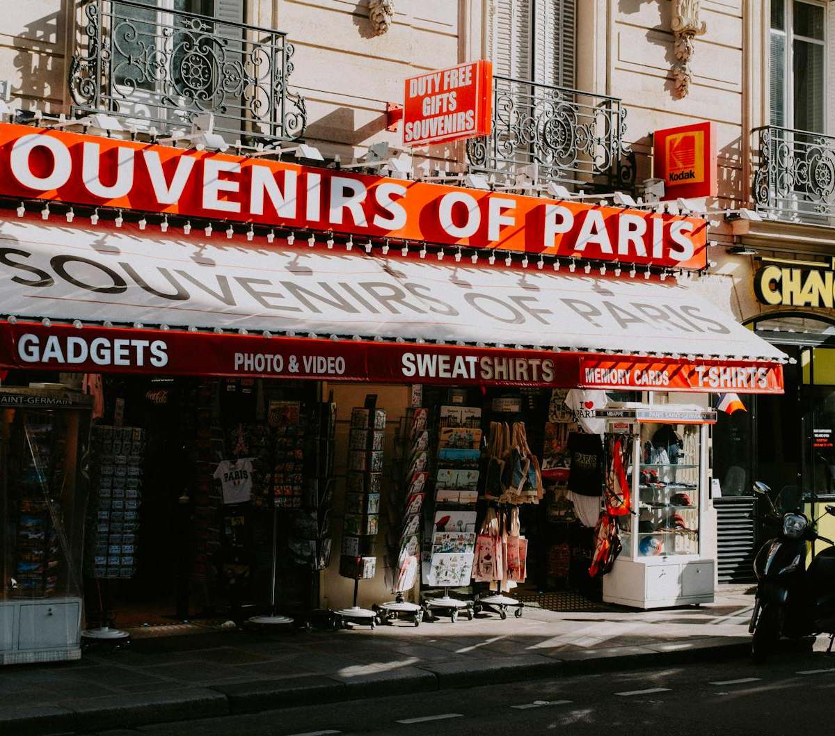 Street view of a Paris souvenir shop with motorbikes, showcasing signage and storefront items.