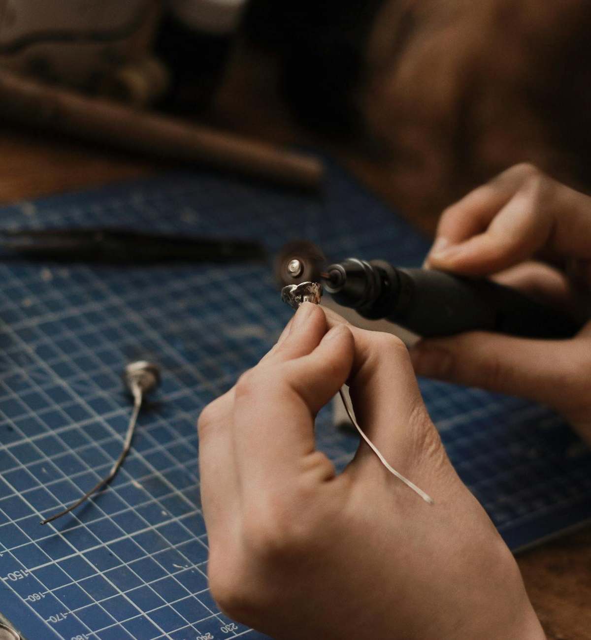 Artisan polishing silver jewelry with precision in a workshop setting.