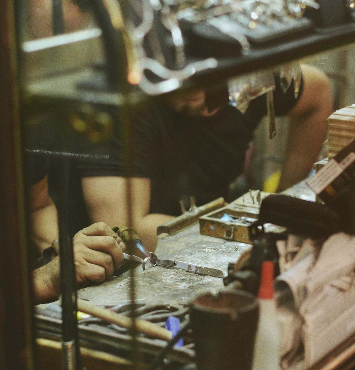 Close-up of an artisan at work in a jewelry workshop, focusing on craftsmanship and tools.