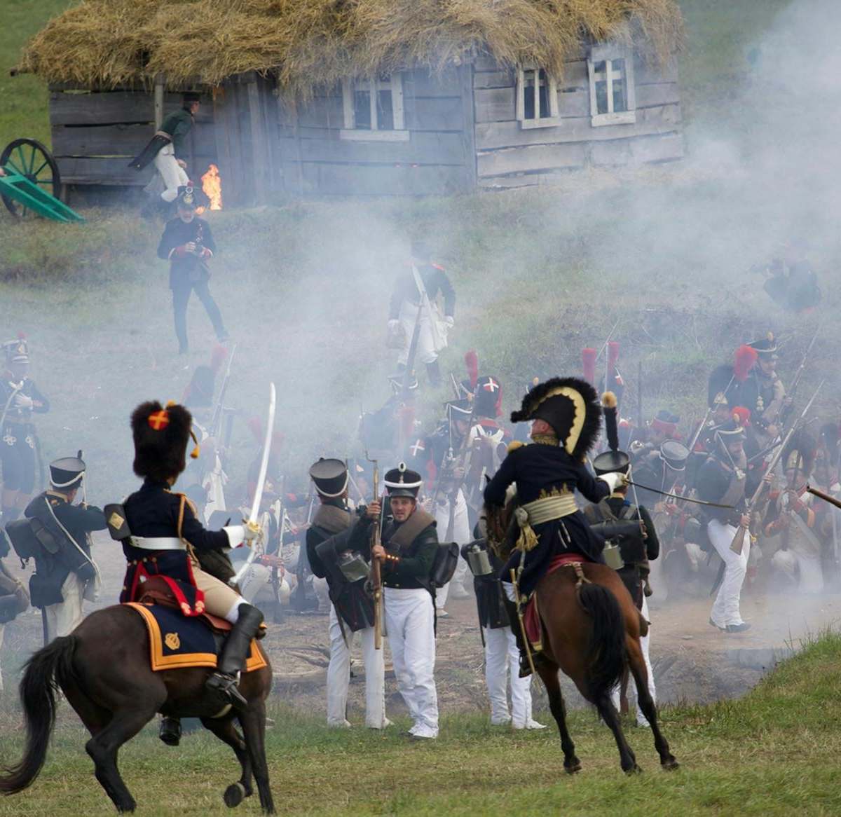 Horse mounted officers and soldiers with rifles and muskets fighting on field in countryside during reenactment of Napoleonic war