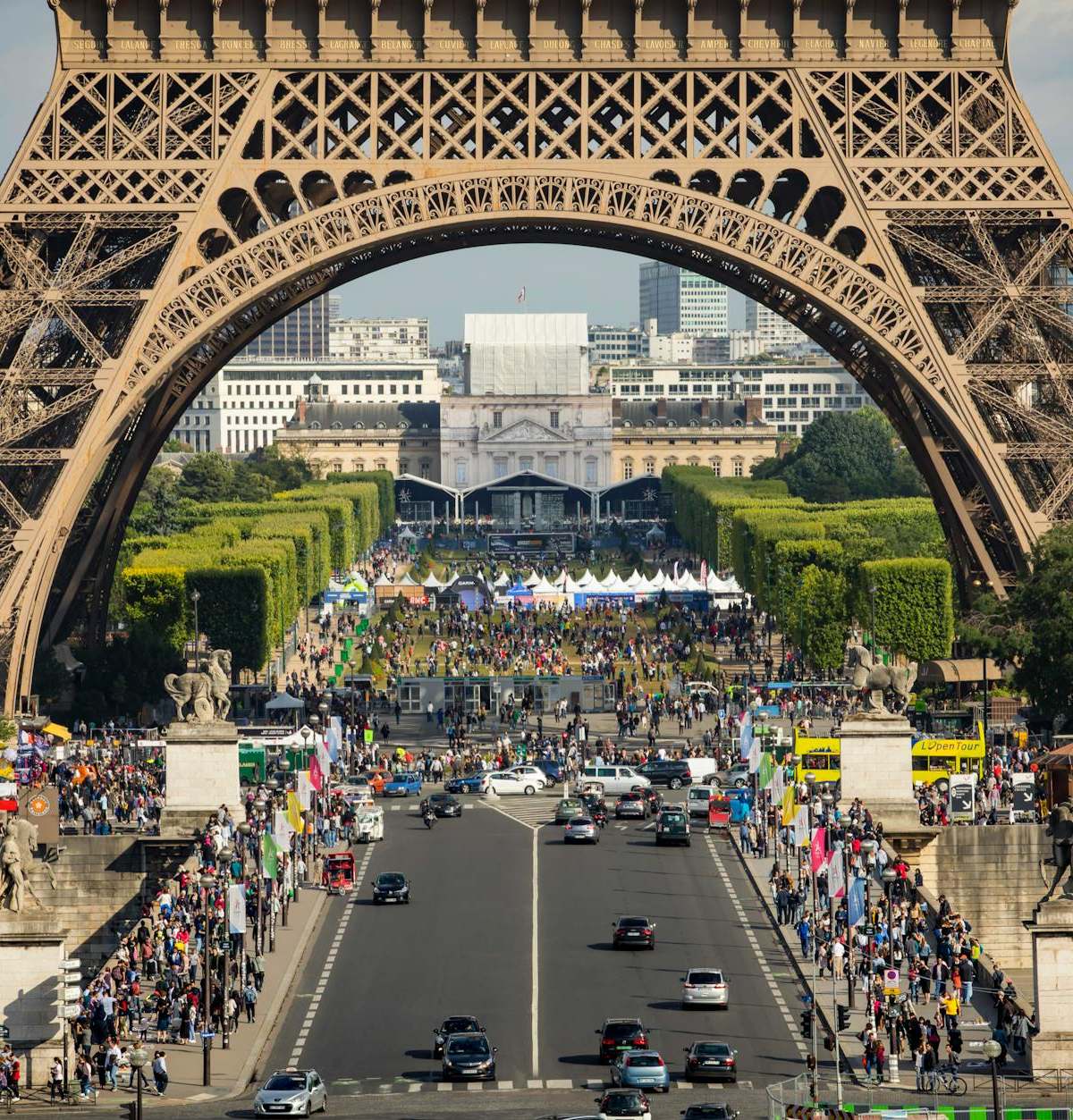 Eiffel Tower framing a bustling street scene in Paris with vibrant activity and landmarks.