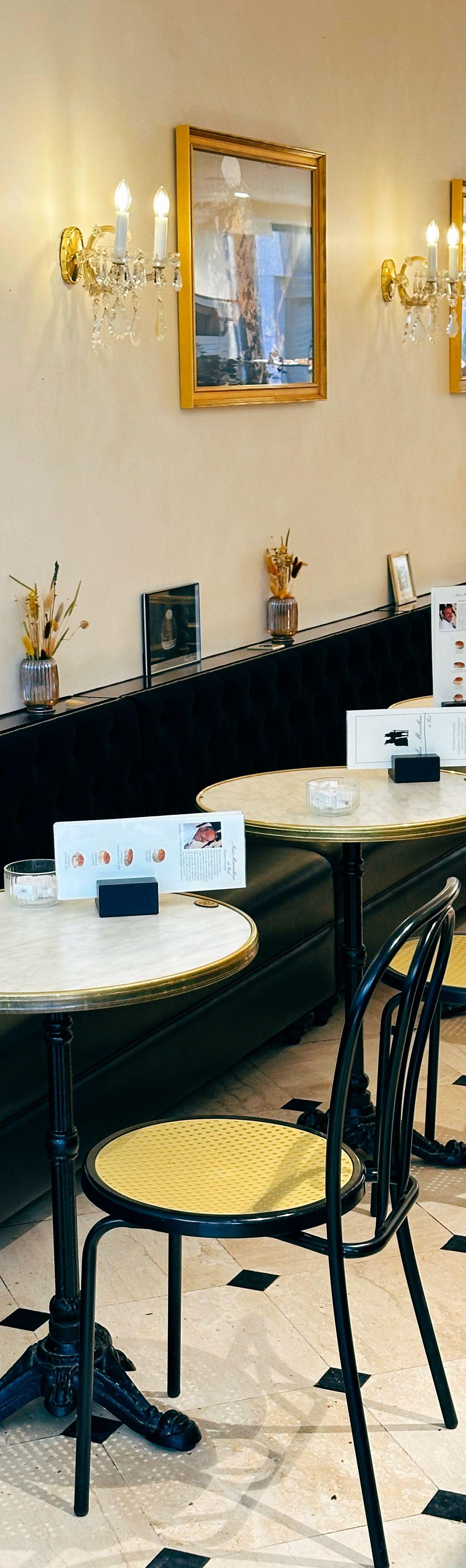 A Paris cafe interior with marble tables, dark banquettes and warm wall lights