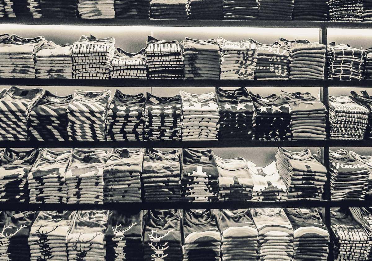 Black and white image showcasing neatly folded t-shirts stacked on store shelves.