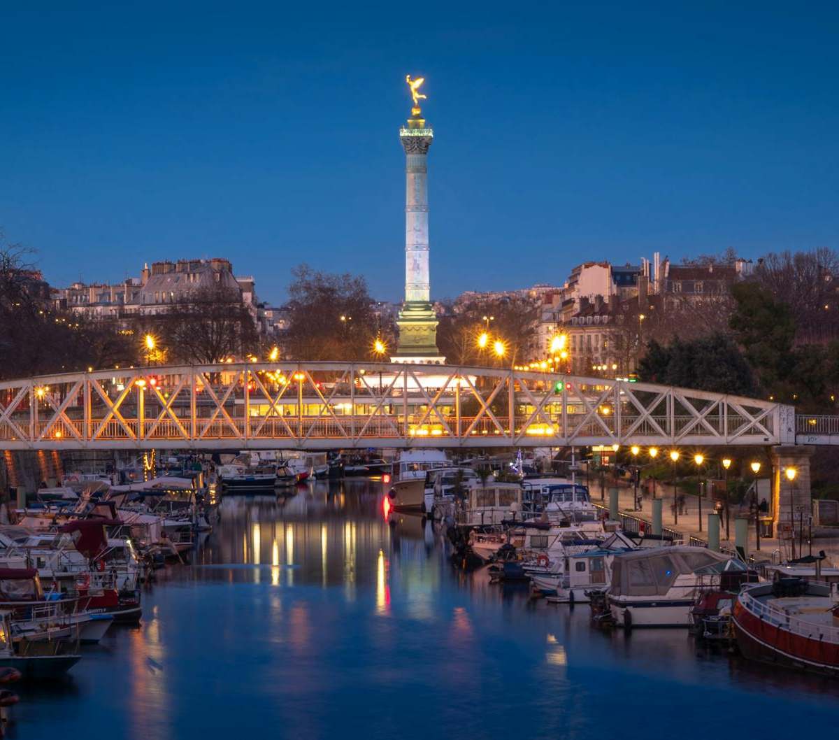 Scenic evening view of the Bastille Square and boats on Canal Saint-Martin in Paris, France.