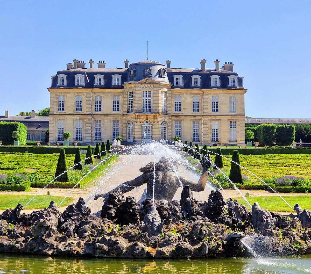 Explore the stunning gardens and architecture of Château de Champs-sur-Marne during a bright summer's day.