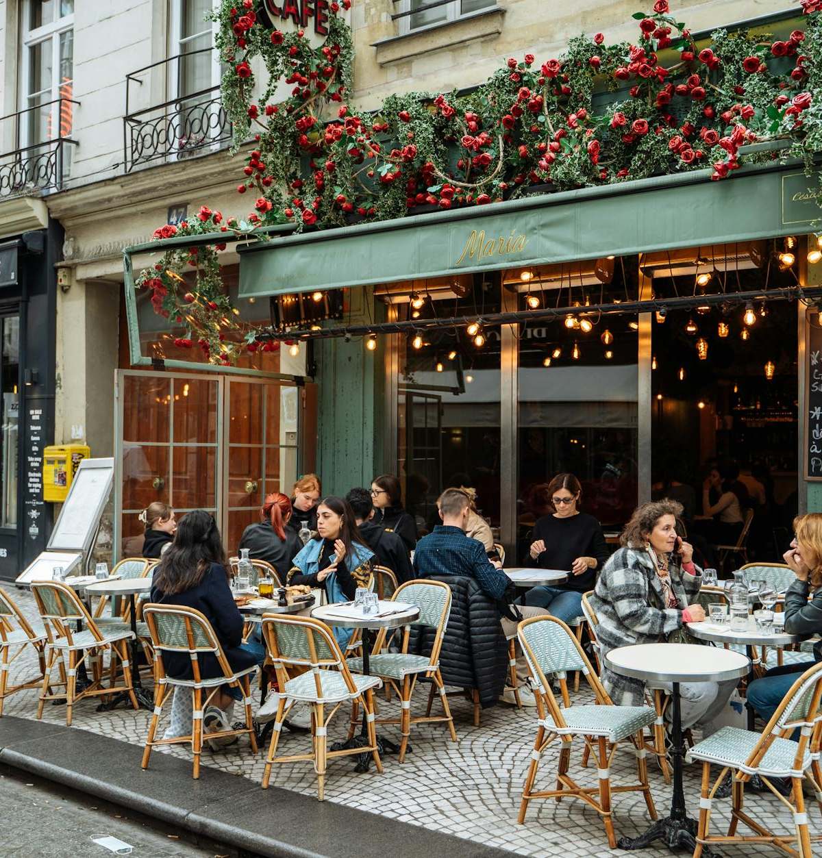 A lively street scene of a Parisian cafe with vibrant outdoor ambiance and dining.