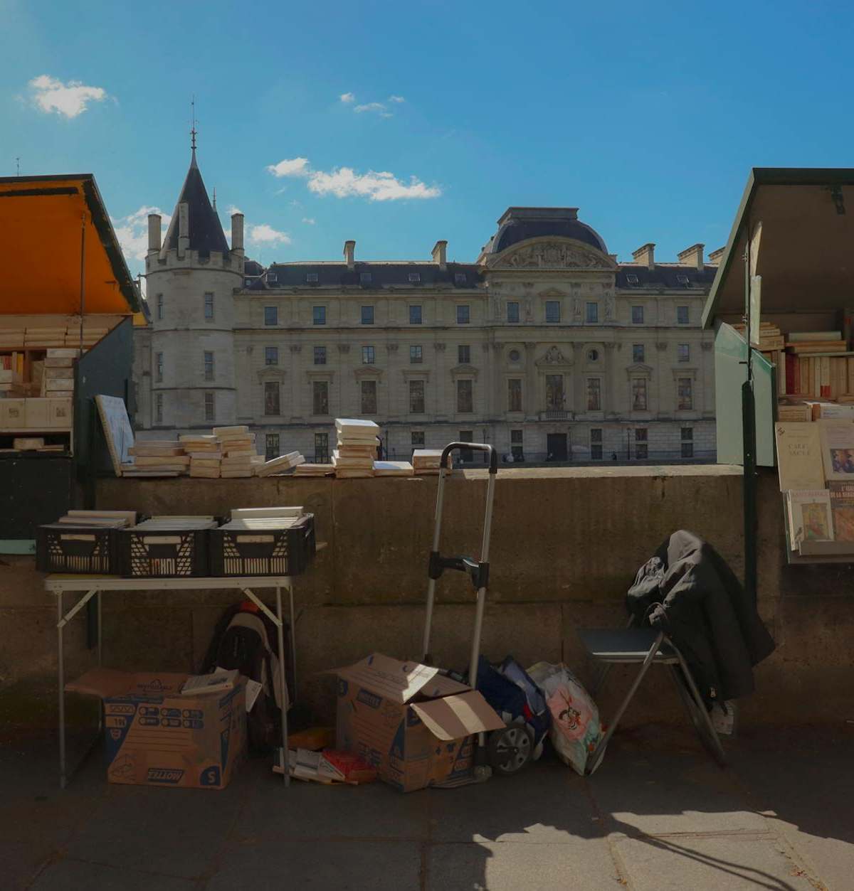 Iconic green bouquiniste boxes along Paris Seine river, showcasing books and prints under historic bridges