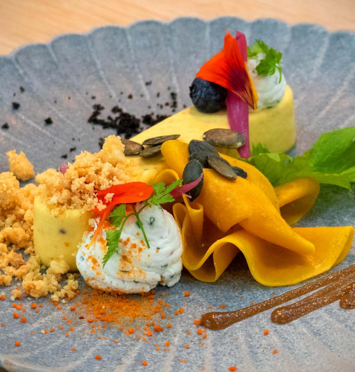 Delicately presented gourmet dish with vibrant colors and artistic flair on a textured plate.