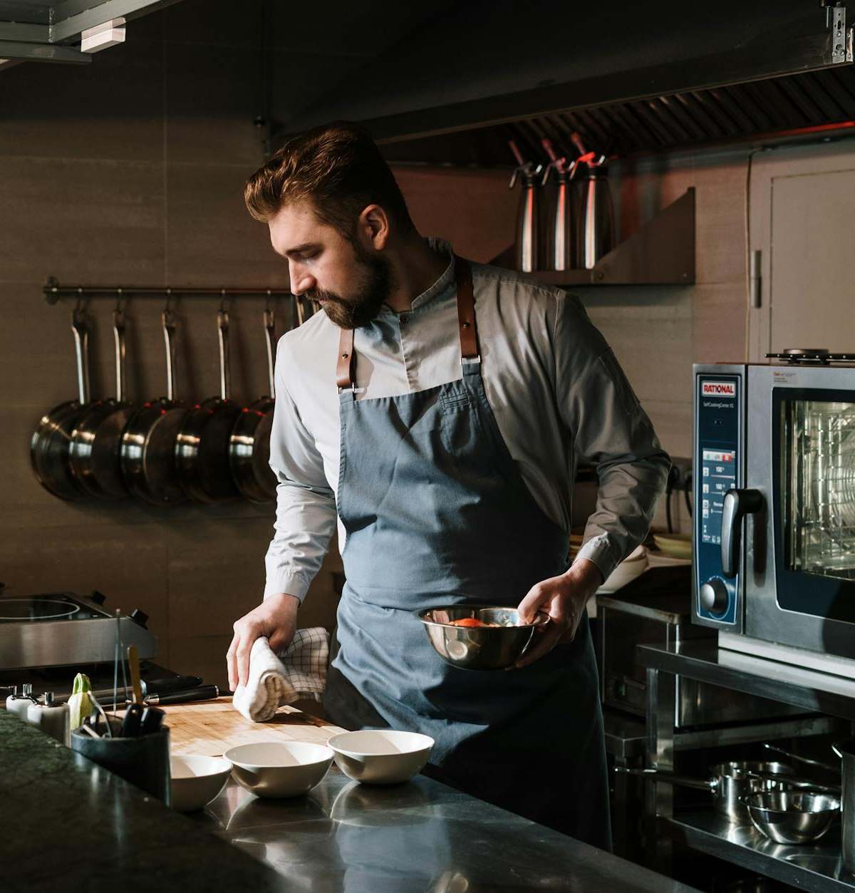 Male chef in a restaurant kitchen preparing a dish, showcasing culinary skills and expertise.