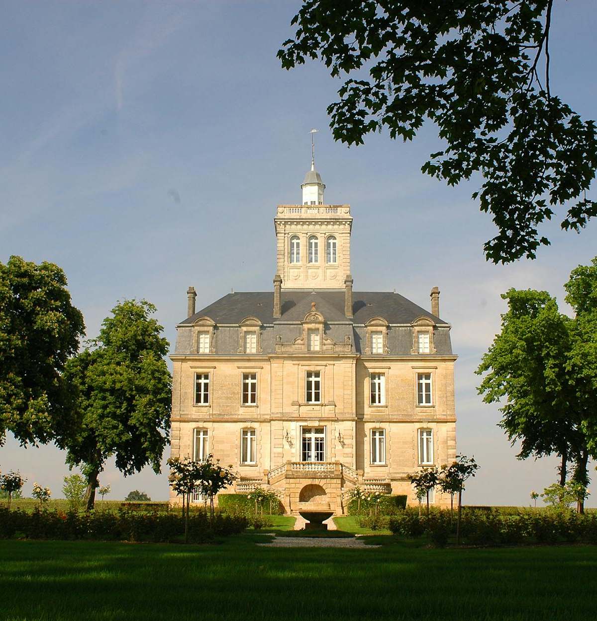 A majestic chateau with lush gardens and blue skies, capturing classic architecture.