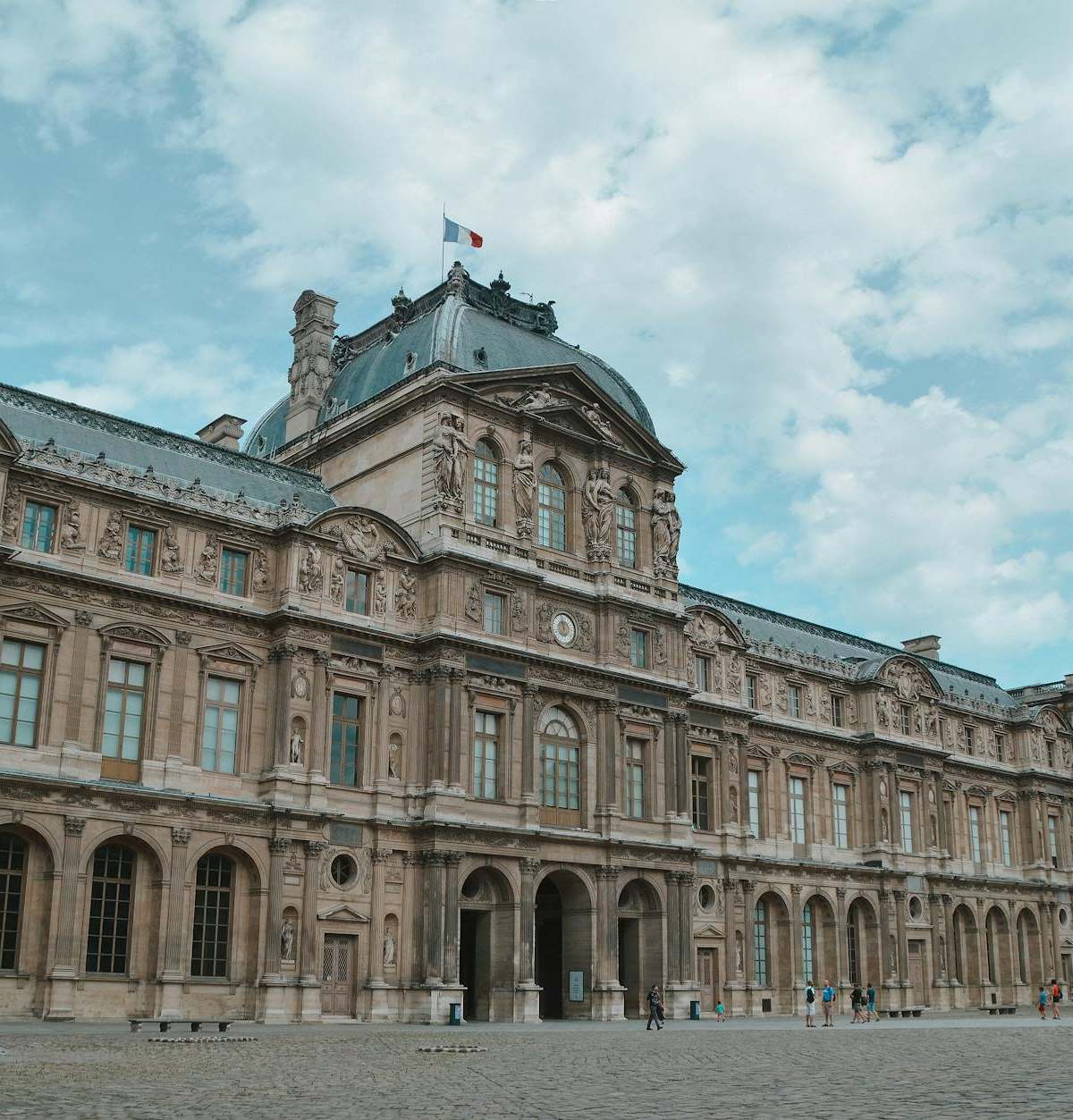 Facade of the Louvre Museum in Paris, showcasing stunning architecture under a bright sky.