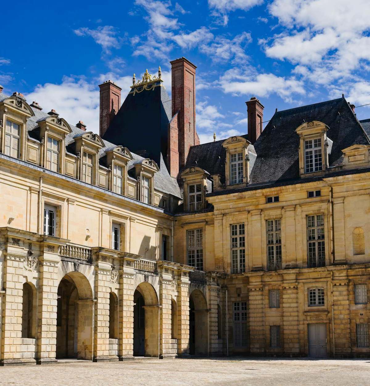 Stunning view of the Château de Fontainebleau under a vibrant blue sky, showcasing its historic architecture.