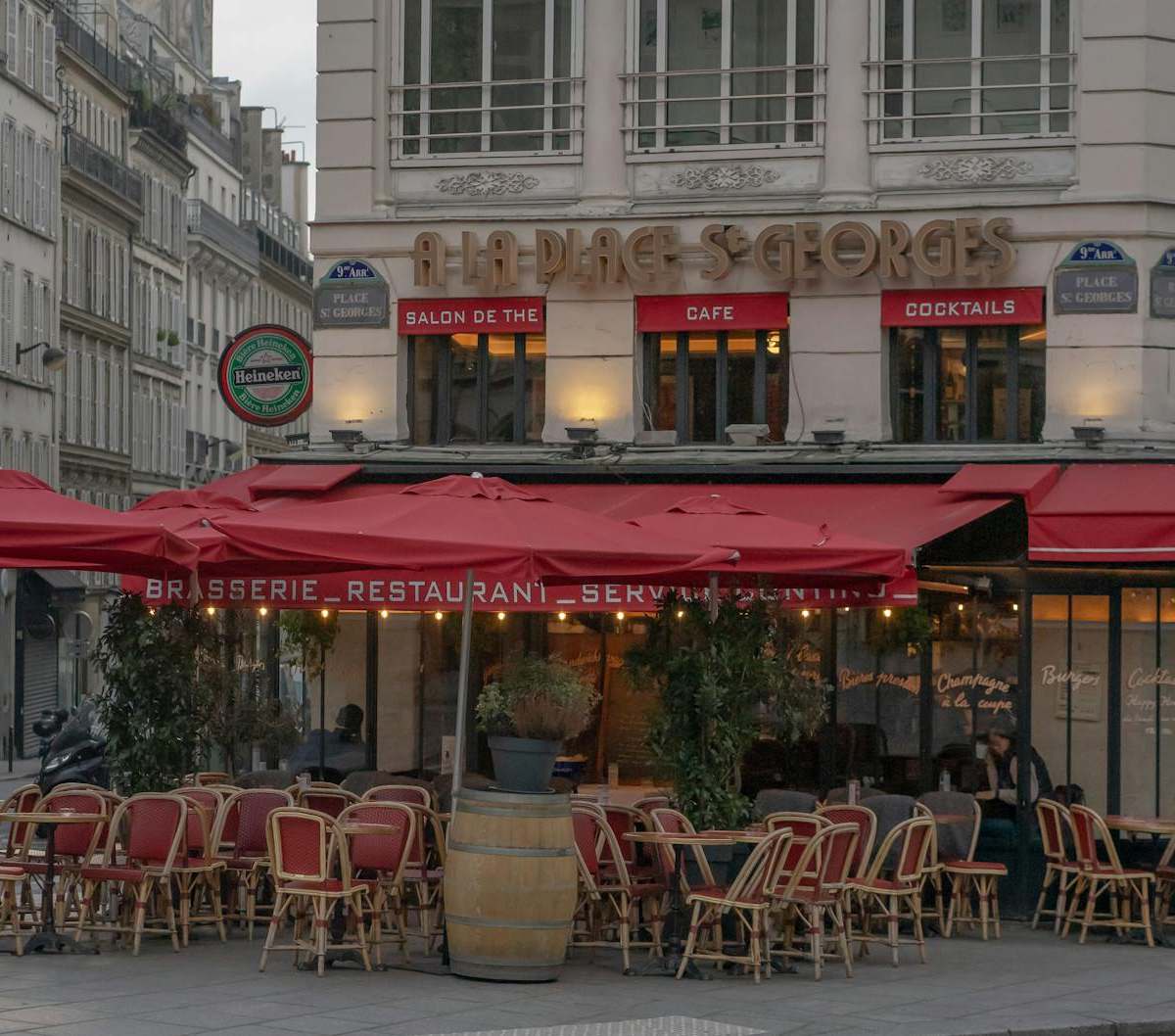 Cozy outdoor seating at a Parisian cafe with red awnings and classic architecture.