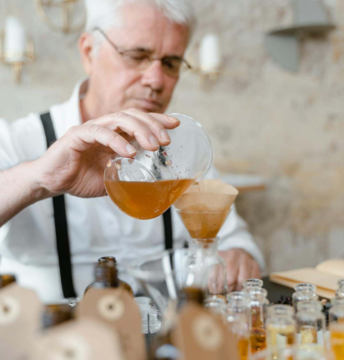 Senior man carefully blends ingredients to create perfume in a cozy workshop.