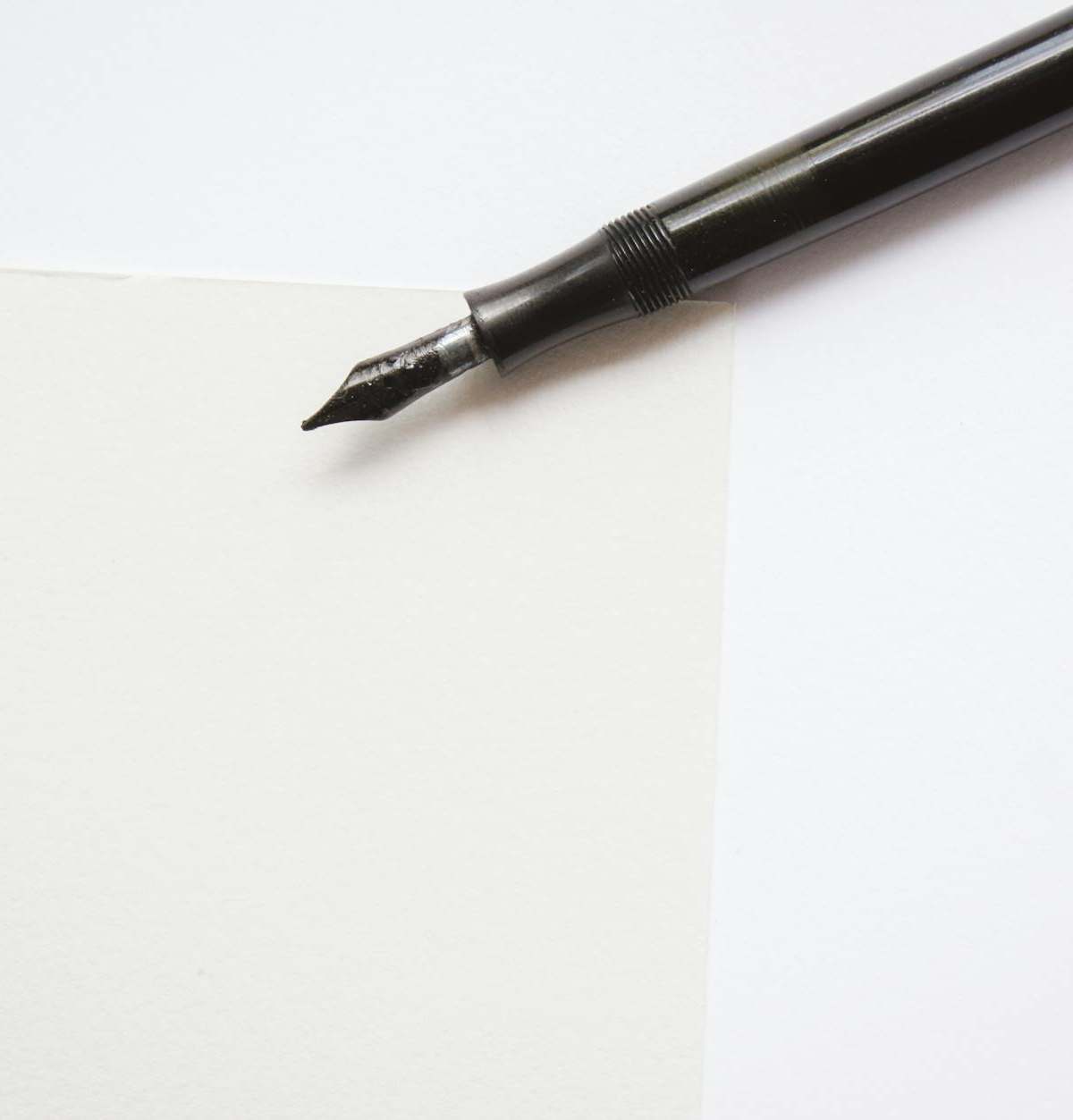 A close-up image of an elegant fountain pen resting on blank white paper, perfect for writing themes.